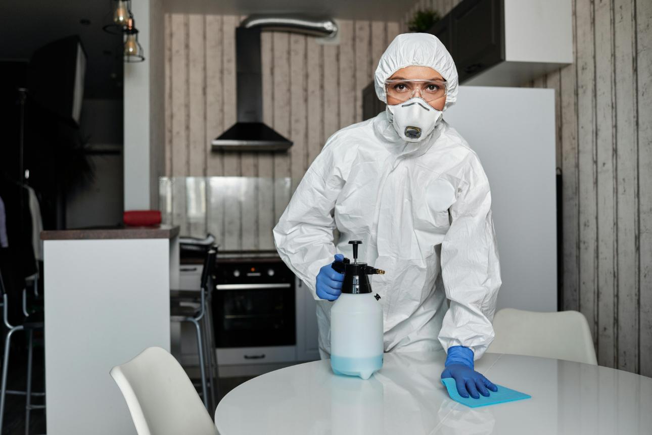 Mujer con traje blanco limpiando una cocina